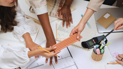Grupo colaborando em projeto com régua, papéis e materiais de escritório sobre a mesa.