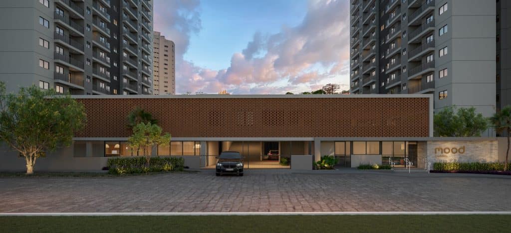 Imagem de um empreendimento imobiliário com prédios modernos e fachada estilosa, com carros estacionados na área externa e iluminação suave ao fundo.