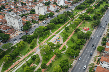 Vista aérea de parque urbano com ciclovias e áreas verdes entre duas avenidas.