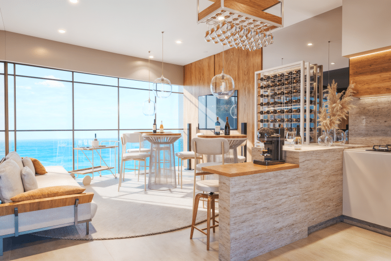 Interior de um apartamento de luxo com vista para o mar, apresentando uma área de estar com sofá e mesa de bar, além de uma cozinha moderna com adega de vinhos. A iluminação suave e os detalhes em madeira criam um ambiente aconchegante.
