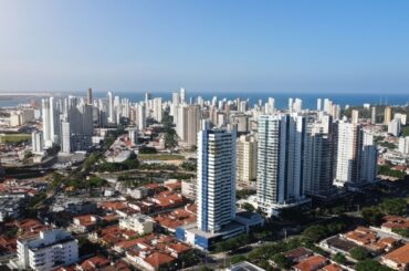 Vista aérea de cidade litorânea com muitos prédios altos e mar ao fundo.