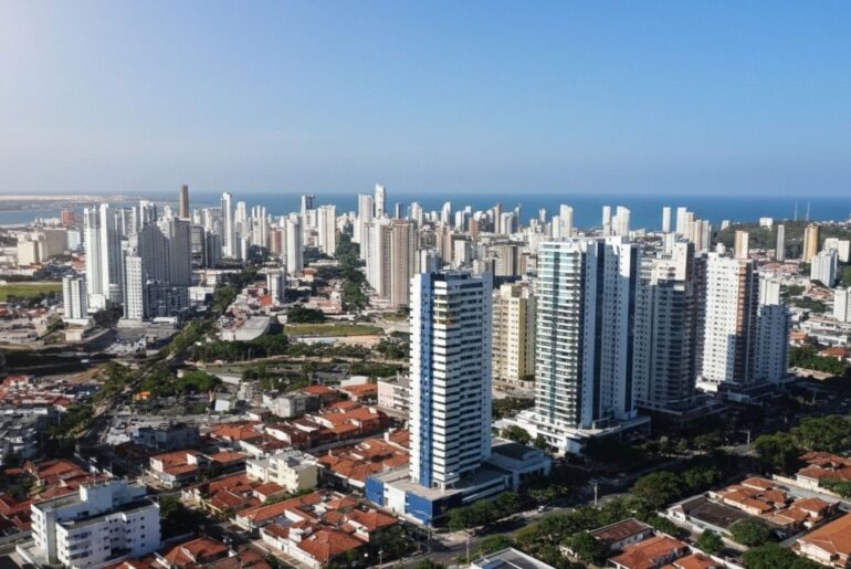 Vista aérea de cidade litorânea com muitos prédios altos e mar ao fundo.